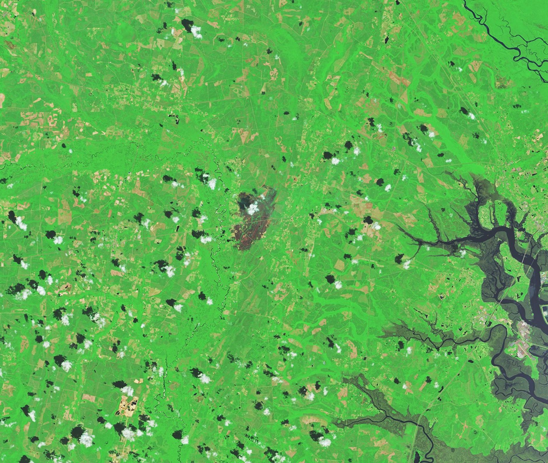 A patch of burned area near Atkinson appears gray amid a background of green. Small scattered clouds are visible in the lower part of the image.